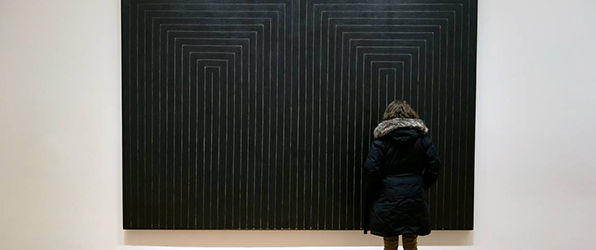 Photograph of museum visitor in front of Frank Stella's <i>The Marriage of Reason and Squalor, II</i> (1959)